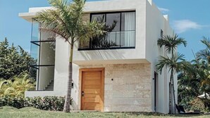 Une maison moderne à deux étages, dotée d’une porte en bois, de grandes fenêtres et d’un balcon.