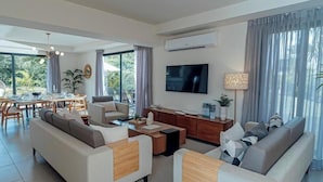 Un salon moderne comprenant un ensemble de canapés, une table basse, un téléviseur et un coin repas avec une table et des chaises.