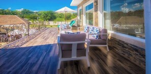 A sunlit patio with outdoor seating, a stone wall, and a view of the landscape.