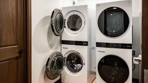 A laundry room with four stacked front-loading washing machines. - Brillion 2‑Bedroom Suite w/ Full Kitchen Near Ariens – Unit #2 (Brillion)