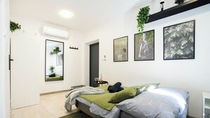 Un dormitorio moderno con cama, mesita de noche, espejo y una obra de arte en la pared.