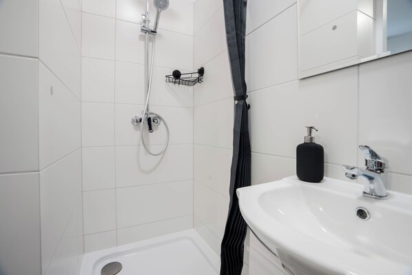 A modern bathroom with a shower, a sink, and a mirror.