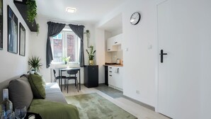 Espacio habitable compacto con sofá, mesa de comedor y kitchenette.