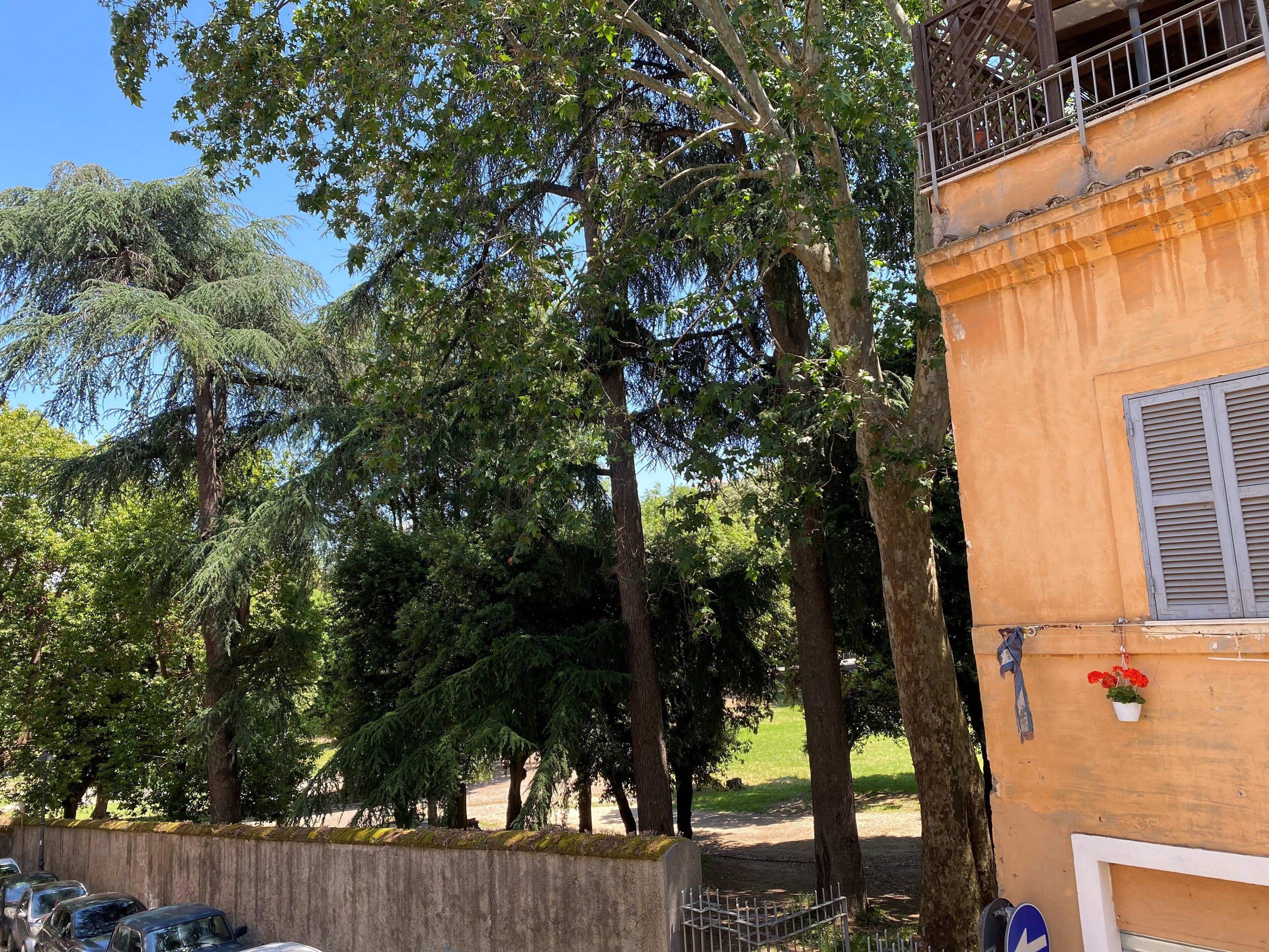 Ein Gebäude mit einem Balkon und einem Gartenbereich mit Bäumen und einem Weg.