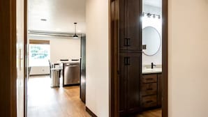 A modern kitchen with wooden cabinets, a stainless steel dishwasher, and a large mirror above the sink. - Brillion 2‑Bedroom Suite w/ Full Kitchen Near Ariens – Unit #4 (Brillion)