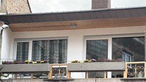 En bygning med balkon, store vinduer og blomsterkasser.