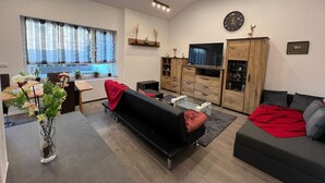 En moderne stue med sofa, sofabord, fjernsyn og spiseplads med bord og stole.