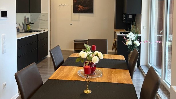Et moderne spiseområde med et træbord, sorte stole og en vase med blomster.