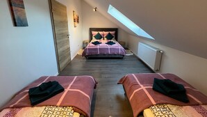 A bedroom with two beds, a skylight, and a wooden door. - ❤ VipStay the stylish 53m² suite with kitchen, balcony, parking, WiFi, SmartTV ❤ (Wiesloch)