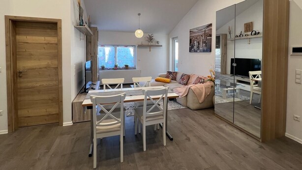 A modern living room with a dining area, a large mirror, and a cityscape painting. - ❤ VipStay the stylish 53m² suite with kitchen, balcony, parking, WiFi, SmartTV ❤ (Wiesloch)