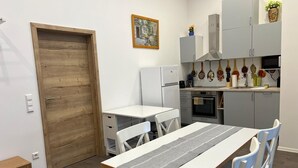 A modern kitchen with white cabinetry, a wooden door, a dining table with chairs, and a kitchen island. - ❤ VipStay the stylish 53m² suite with kitchen, balcony, parking, WiFi, SmartTV ❤ (Wiesloch)