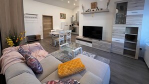 A modern living room with a sofa, TV, and dining area. - ❤ VipStay the stylish 53m² suite with kitchen, balcony, parking, WiFi, SmartTV ❤ (Wiesloch)