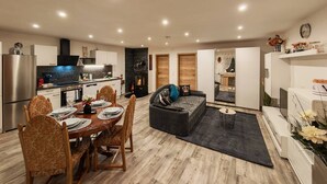 Et moderne køkken med spiseområde, pejs og en stue med sofa og sofabord.