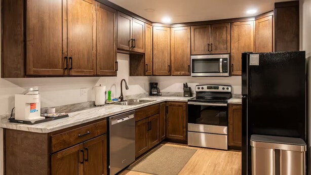 A modern kitchen with wooden cabinets, stainless steel appliances, and a marble countertop. - Brillion 2‑Bedroom Suite w/ Full Kitchen Near Ariens – Unit #5 (Brillion)
