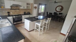 Une cuisine dotée d’un îlot central, de meubles blancs, d’une cuisinière et d’un évier.