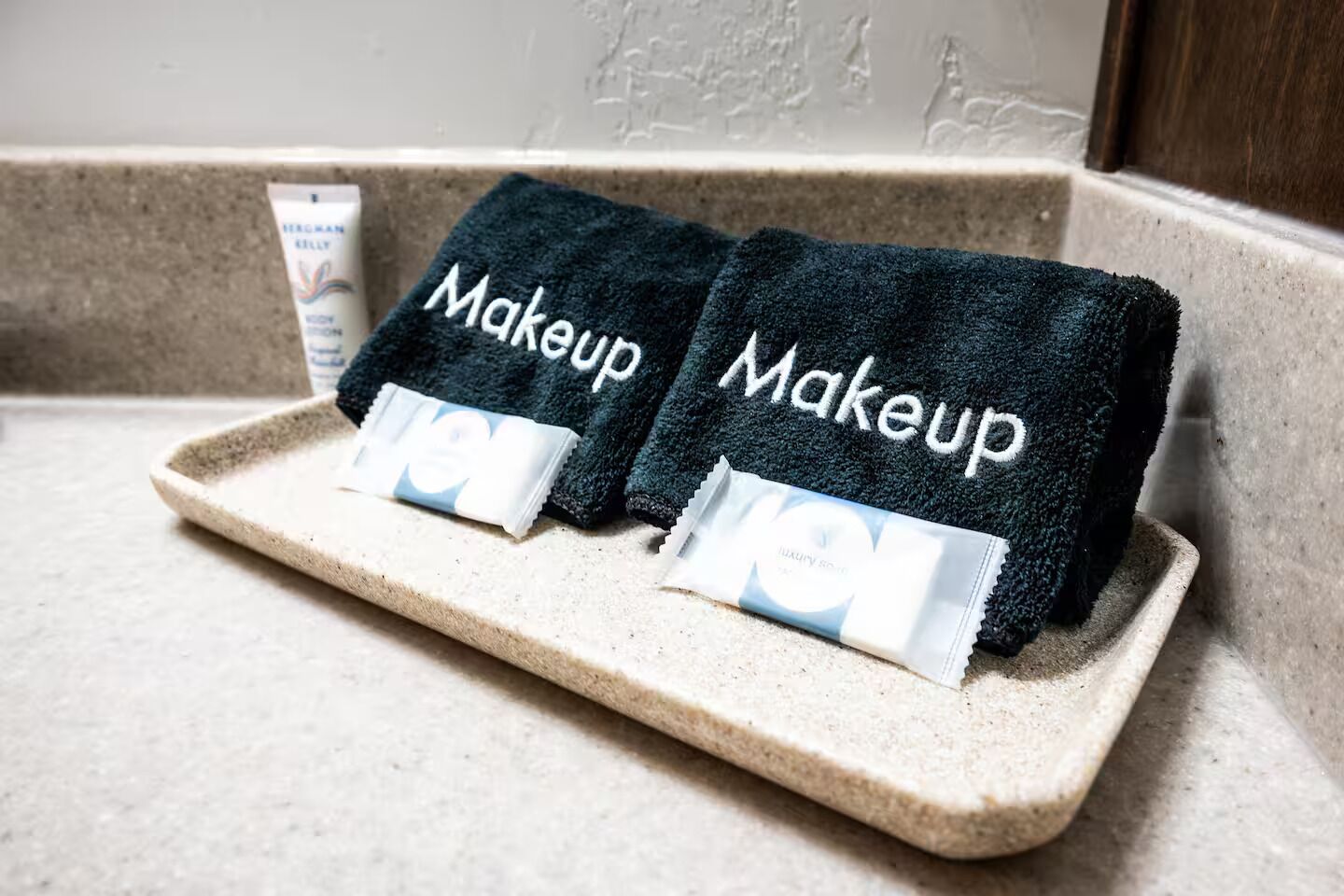 Zwei dunkelblaue Handtücher mit dem Aufdruck 'Makeup', platziert auf einer beigen Ablagefläche.