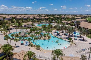 Un resort con varias piscinas, palmeras y un amplio espacio de piscina central.