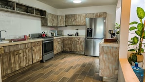 Une cuisine moderne avec des meubles en bois, des appareils électroménagers en acier inoxydable et un sol carrelé.