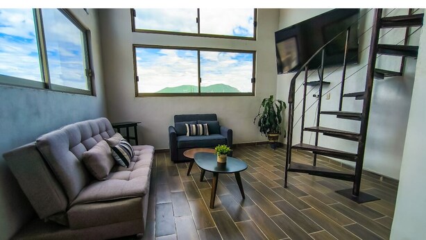 Un salon moderne avec un canapé, une table basse et un escalier.