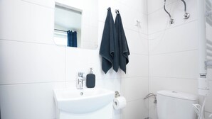 Een badkamer met een wit wastafelmeubel, toilet en handdoekhouder.