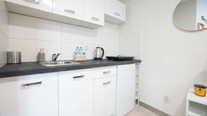 Een moderne keuken met witte kasten, een zwart aanrecht en een roestvrijstalen spoelbak.