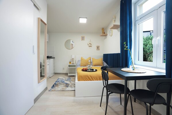 Un dormitorio moderno con cama, mesita de noche y ventana con cortinas.