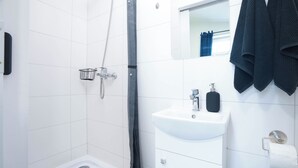 Een moderne badkamer met een douche, een wastafel en een handdoekhouder.