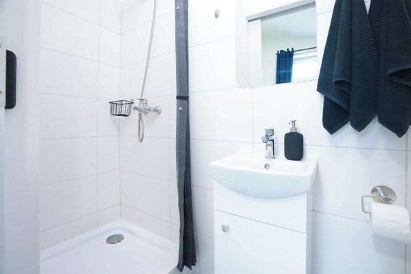 A modern bathroom with a shower, a sink, and a towel rack.