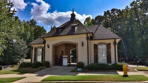 A two-story building with a brick facade, a gabled roof, and a central entrance with a glass door. - The Adele @ Oxford Farms- Tucked off South Lamar! Two Miles from The Square! (Oxford)