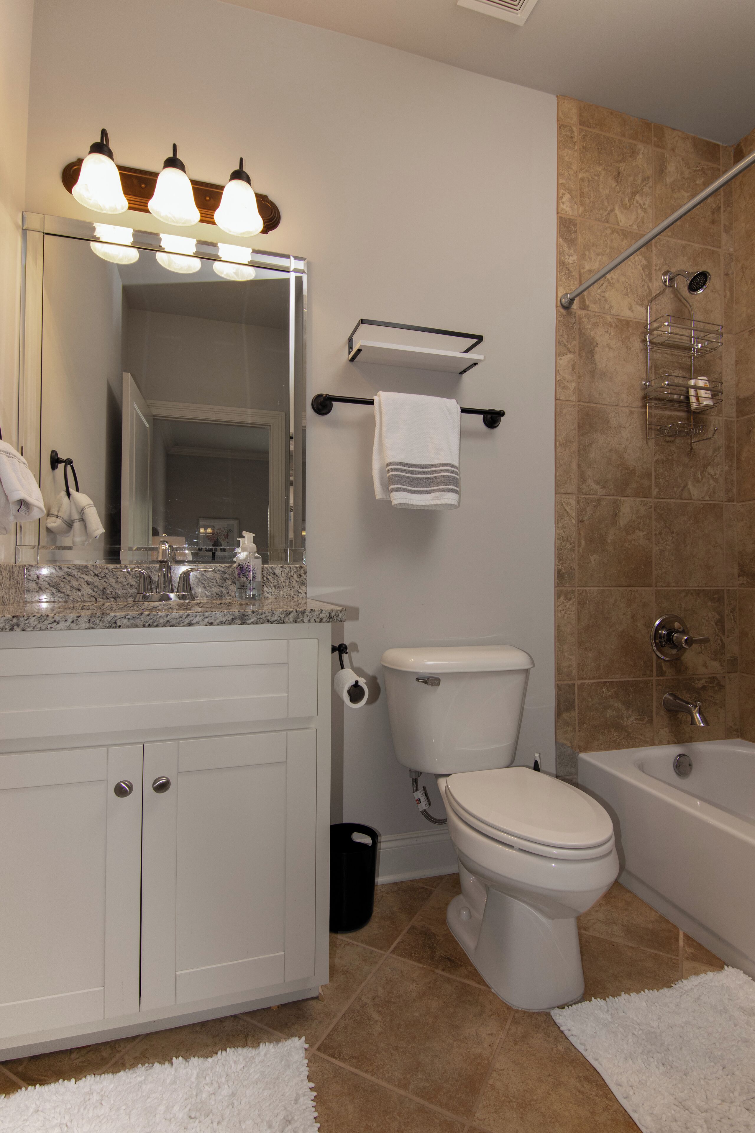A modern bathroom with a marble sink, a toilet, a bathtub, and a shower area.