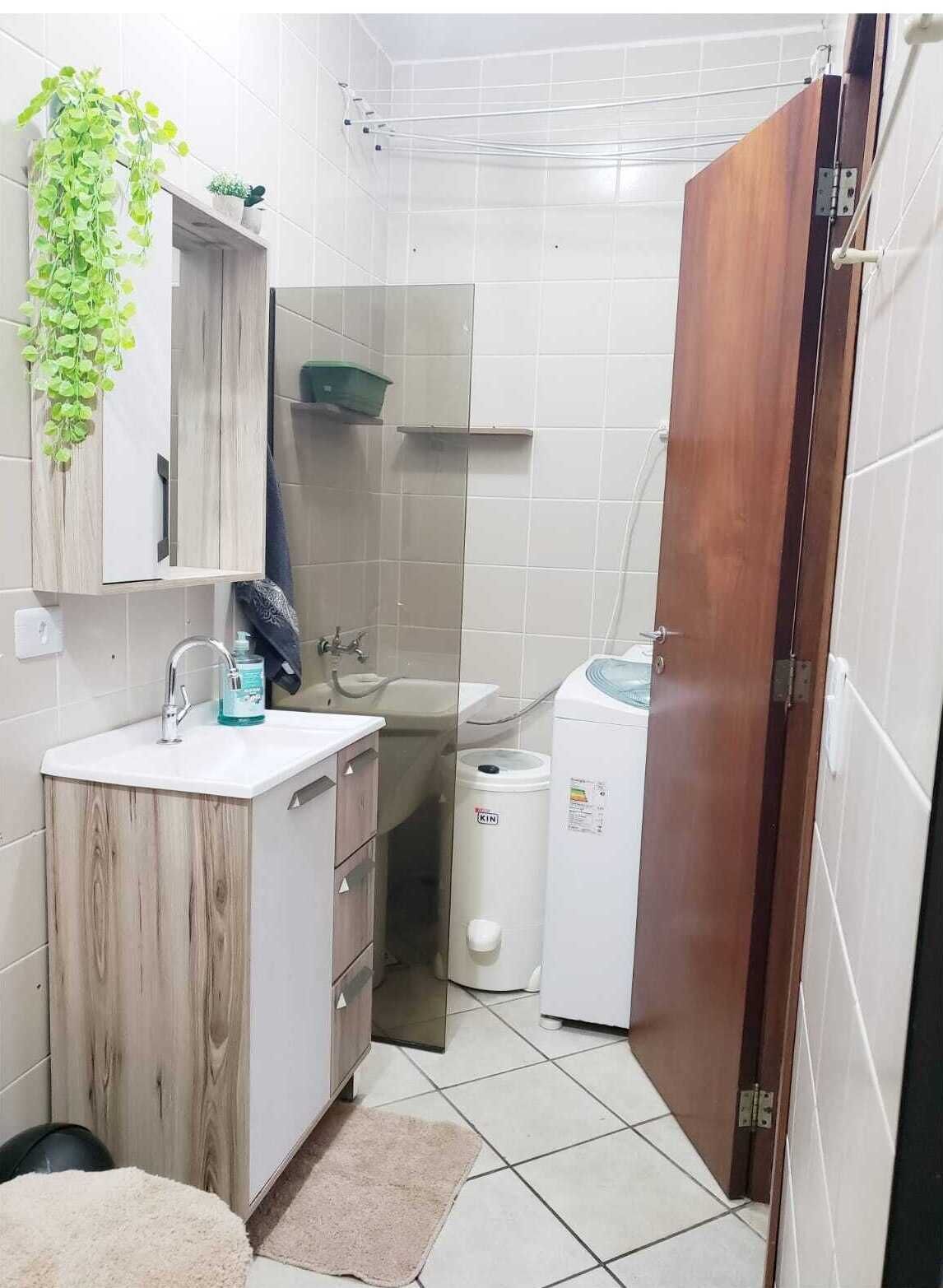 Een kleine badkamer met een houten wastafelmeubel, een wastafel, een spiegel, een handdoekhouder en een toilet.