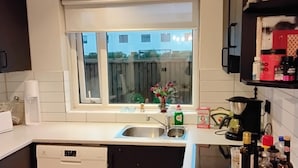 Una cocina moderna con lavavajillas, un lavaplatos y una ventana con vistas a un patio trasero.