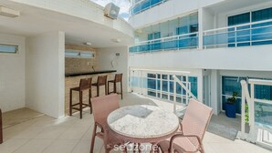 Een modern gebouw met een balkon, voorzien van rieten stoelen en een marmeren tafel.