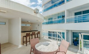 Un bâtiment moderne doté d’un balcon aménagé avec des fauteuils en osier et une table en marbre.