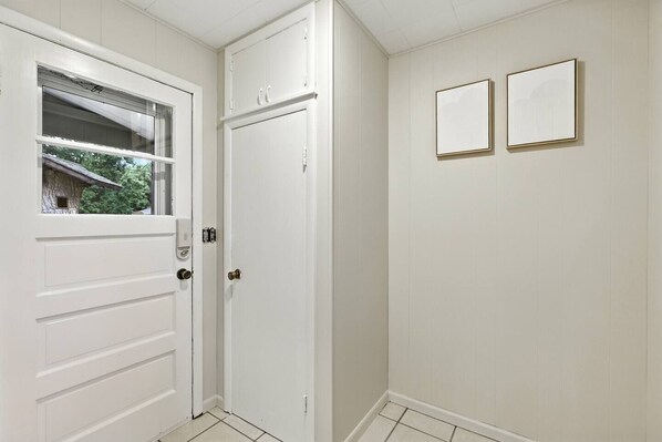 A white door with a window, a small outdoor view, and two framed pictures on the wall.
