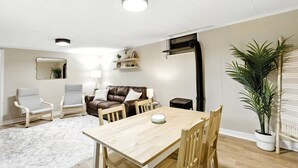 Ein modernes Wohnzimmer mit einem Holzesstisch, zwei Sofas und einer großen Küstpflanze.