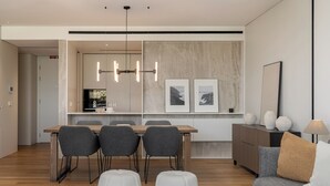 Un salon moderne comprenant un canapé, des poufs, une table basse et un coin repas avec des chaises et une table.
