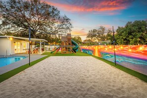 Un pati d'entrada amb piscina, tobogan i espai de jocs.