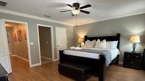 Ein Schlafzimmer mit Bett, Nachttischen, Deckenventilator und einer Bank.