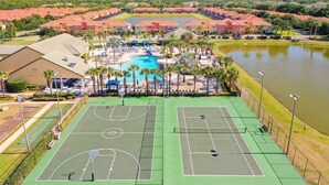 Eine Vogelperspektive eines Sportkomplexes mit mehreren Tennisplätzen, einem Schwimmbad und umliegenden Gebäuden.