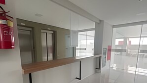 A modern hotel lobby with a long reception desk, a fire extinguisher, and a clean, tiled floor.