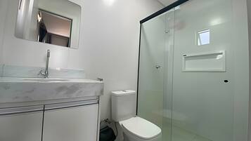 A modern bathroom with a marble sink, a toilet, and a glass shower enclosure.