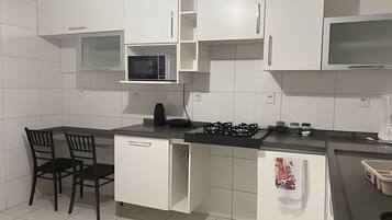 Een koelkast, een microgolfoven, kookgerei, borden en bestek