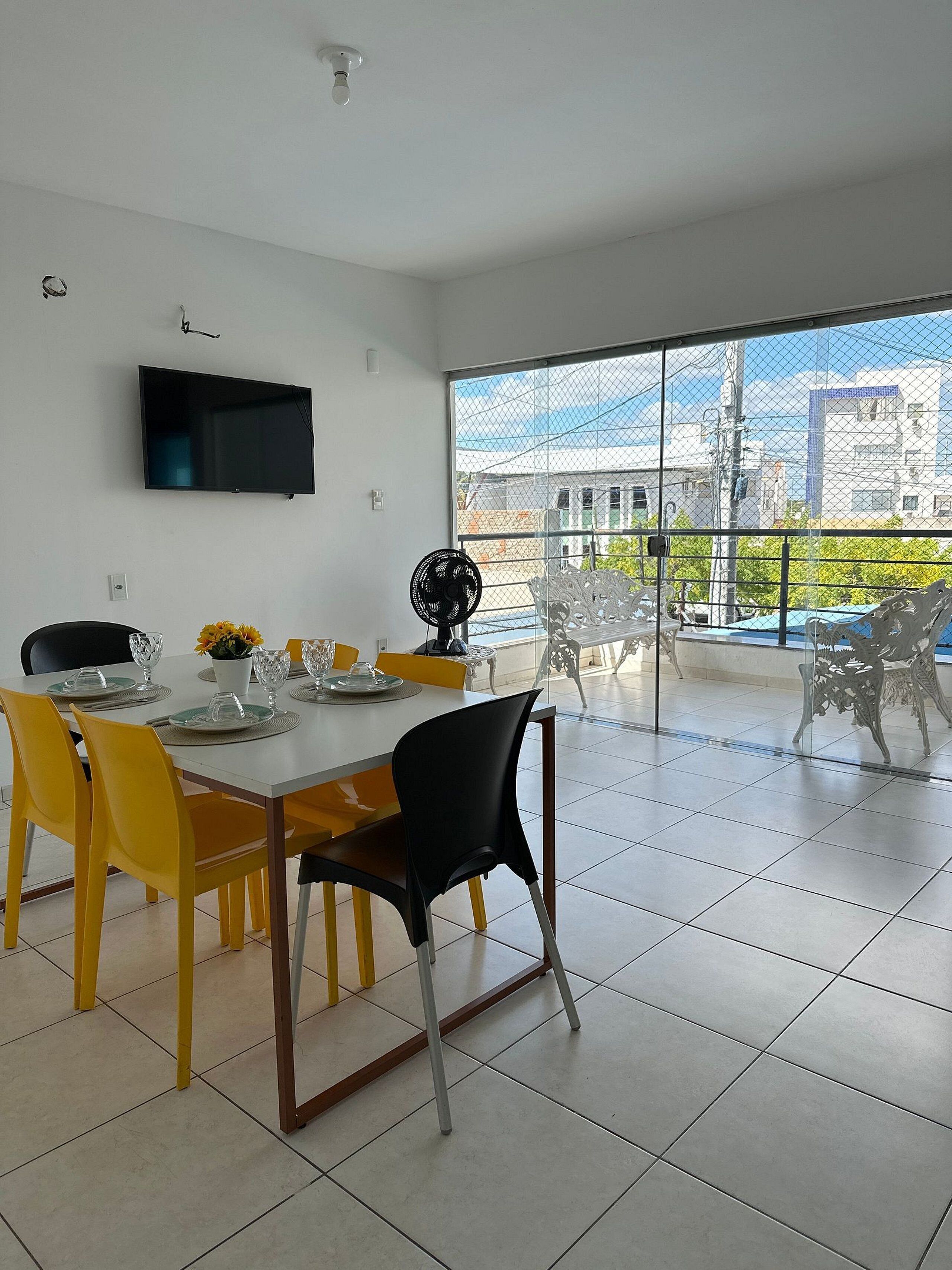 Een moderne eetruimte met een groot raam, een flatscreen-tv en een balkon met buitenmeubilair.