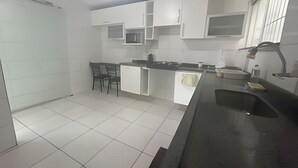 A modern kitchen with white cabinets, a black countertop, and a tiled floor. - Close to the waterfront, 14 people, air conditioning and garage (Petrolina)
