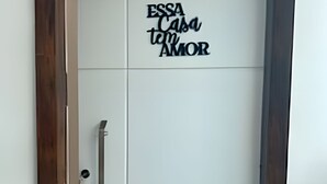 A white door with a wooden frame and a handle. The door has a sign that reads "ESSA Casa tem AMOR". - Close to the waterfront, 14 people, air conditioning and garage (Petrolina)