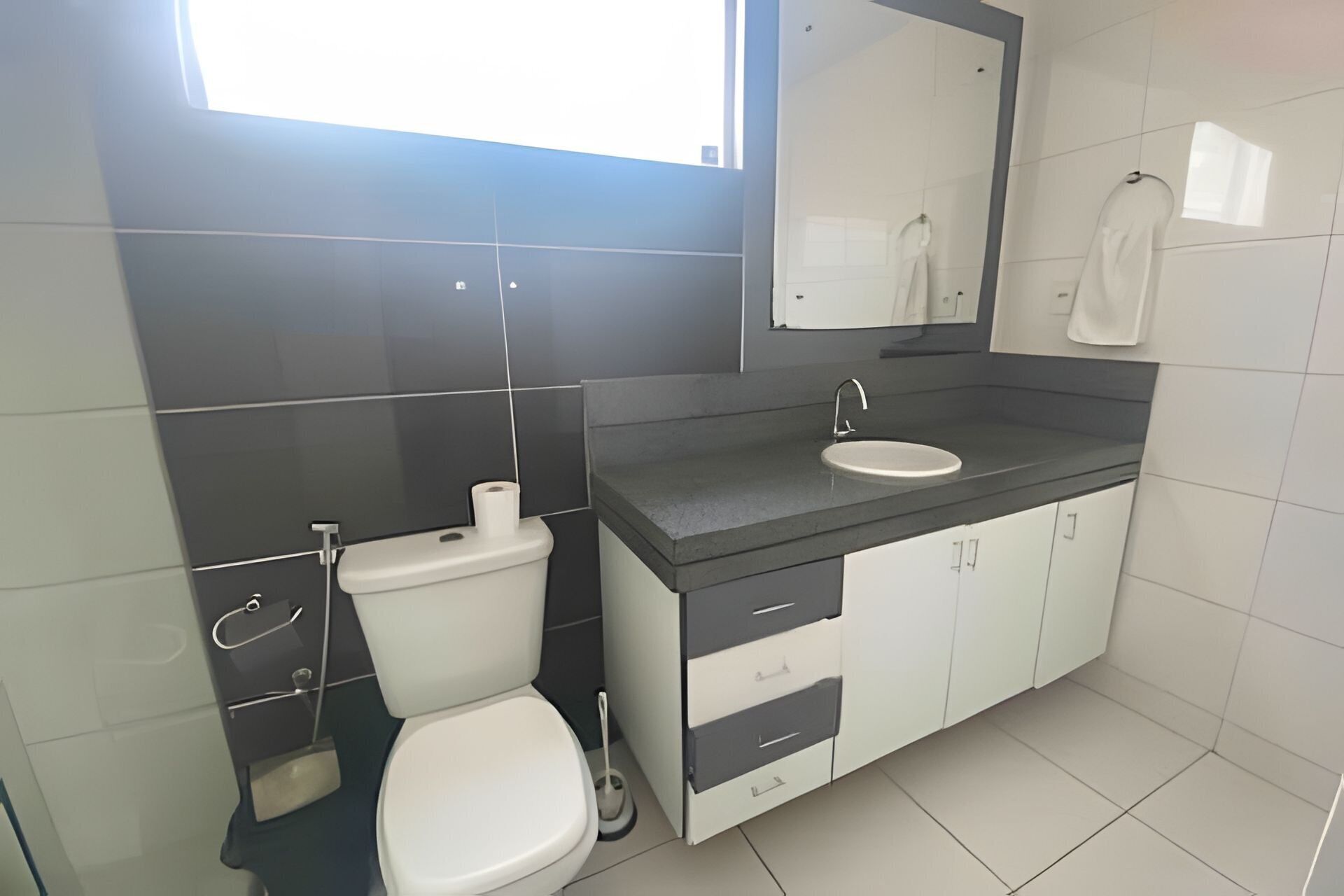A modern bathroom with a toilet, sink, and mirror.
