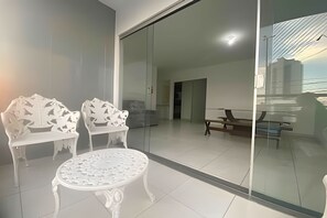 Un soggiorno moderno con una parete divisoria in vetro, arredi bianchi e vista sull'interno.