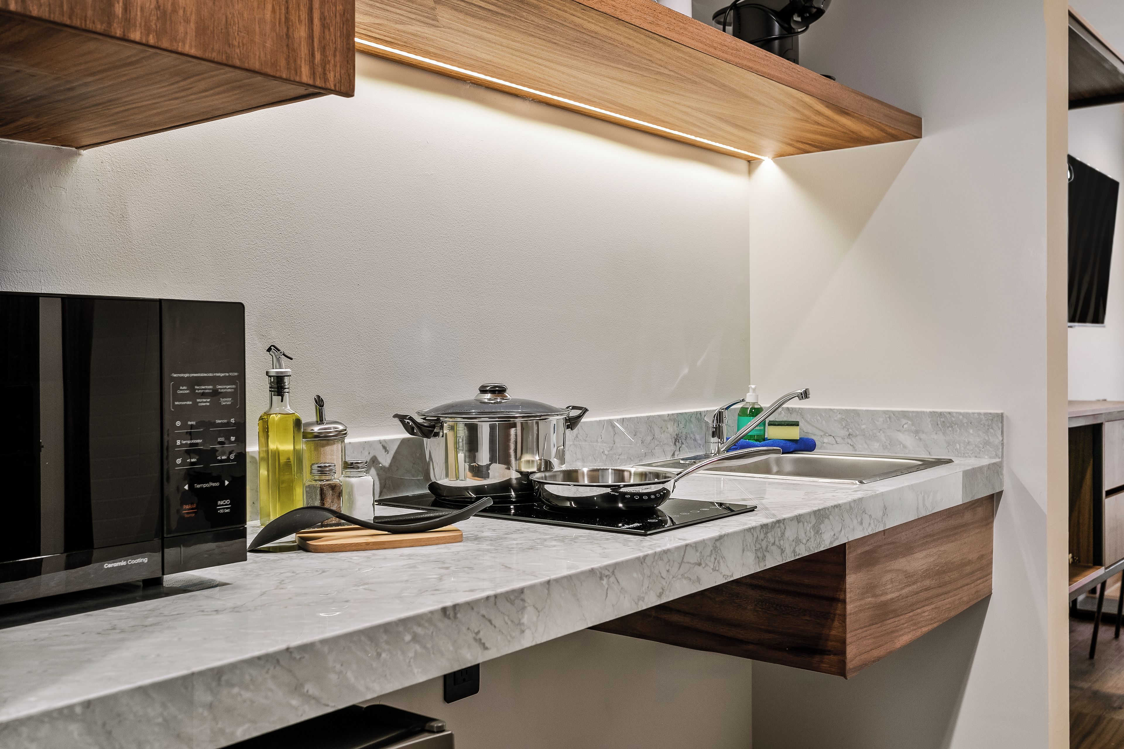 A modern kitchen with a built-in microwave, stove, and a pot on the counter.