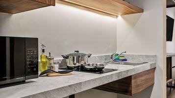 A modern kitchen with a built-in microwave, stove, and a pot on the counter.